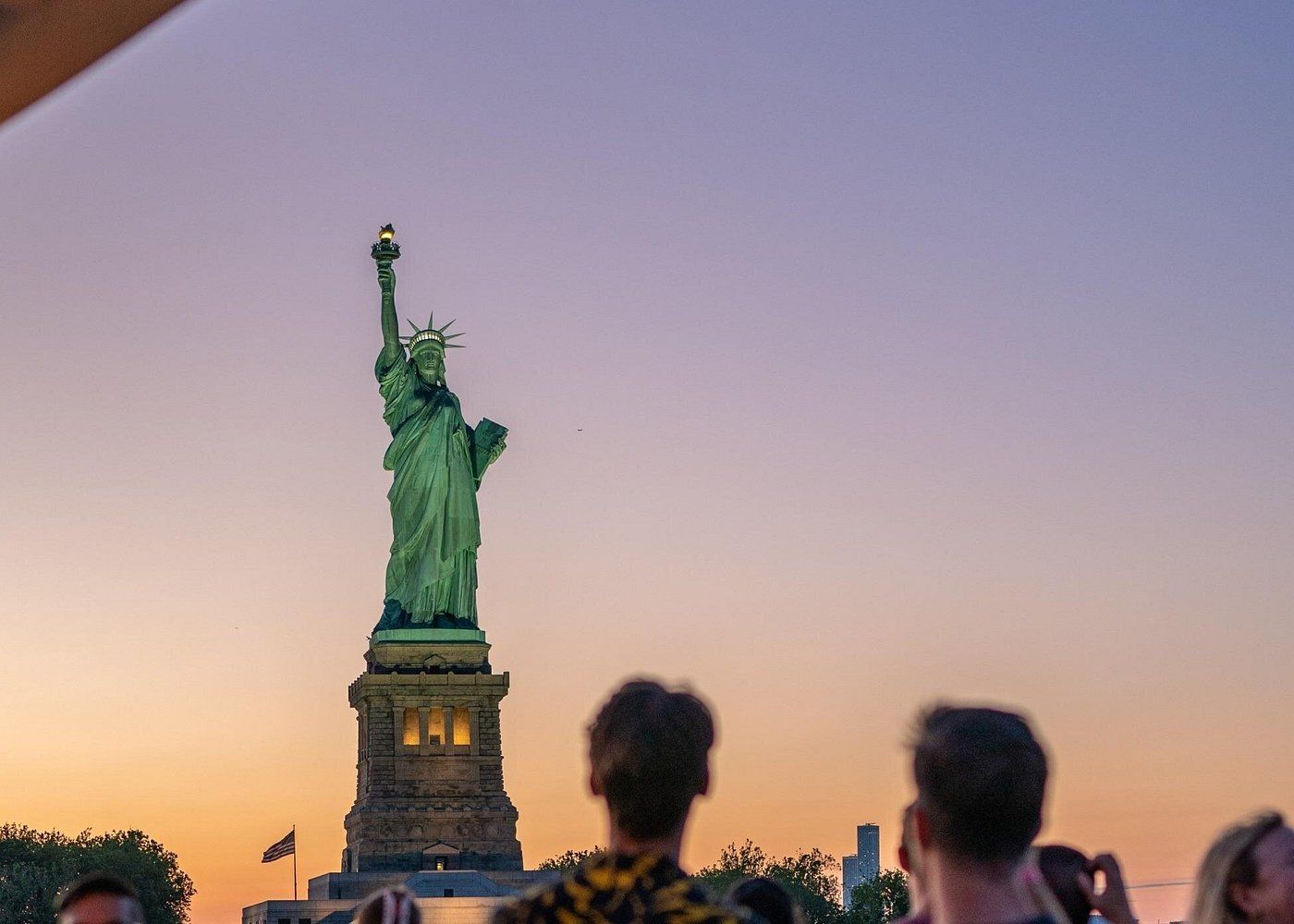 Tourists in front of the Statue of Liberty at sunset