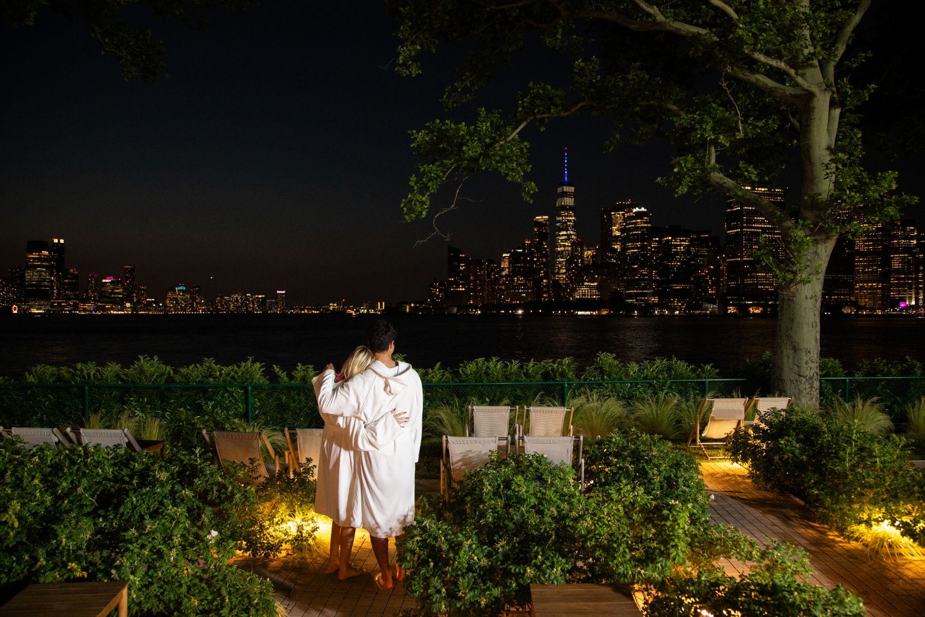 Couple regardant la skyline de New York de nuit depuis le spa de Governors Island